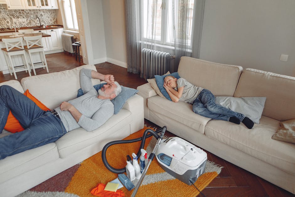 A white upholstered sofa with tufted backrest and rolled arms is positioned against a white paneled wall in a well-lit living room. The sofa is clean and appears to be recently sanitized or deep clean